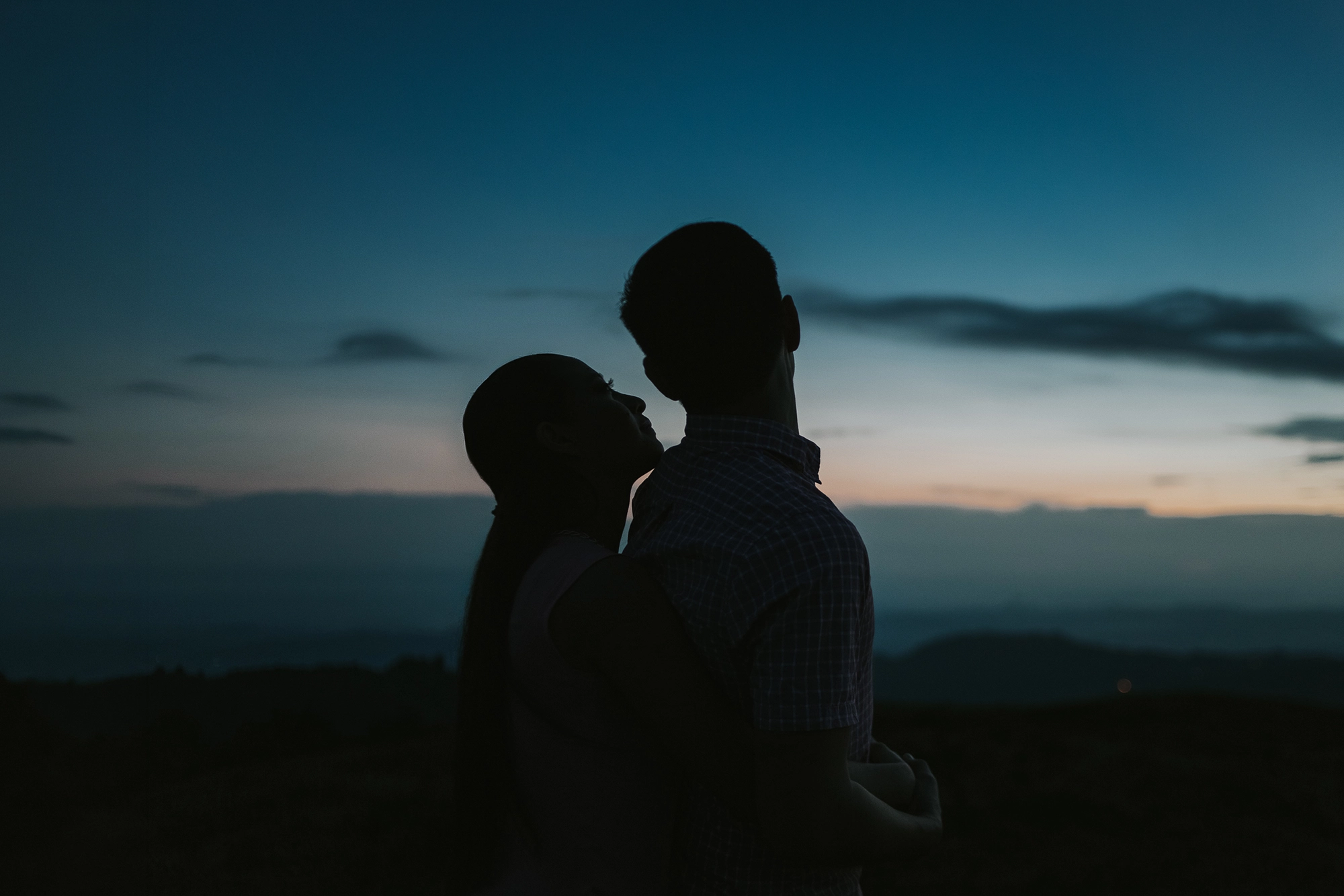 Novios abrazándose al amanecer durante una sesión de fotografía de bodas con luz natural y estilo documental.
