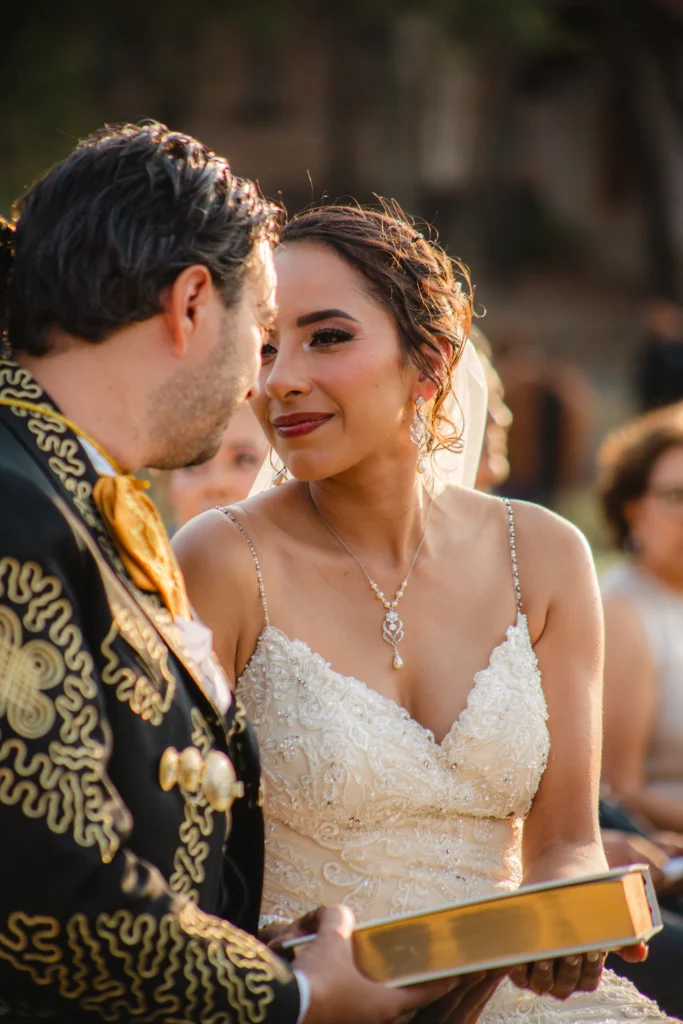 Fotografía de bodas de una pareja de novios mirándose a los ojos en el altar durante la ceremonia. Retrato documental con luz natural que captura la emoción y la conexión del momento.