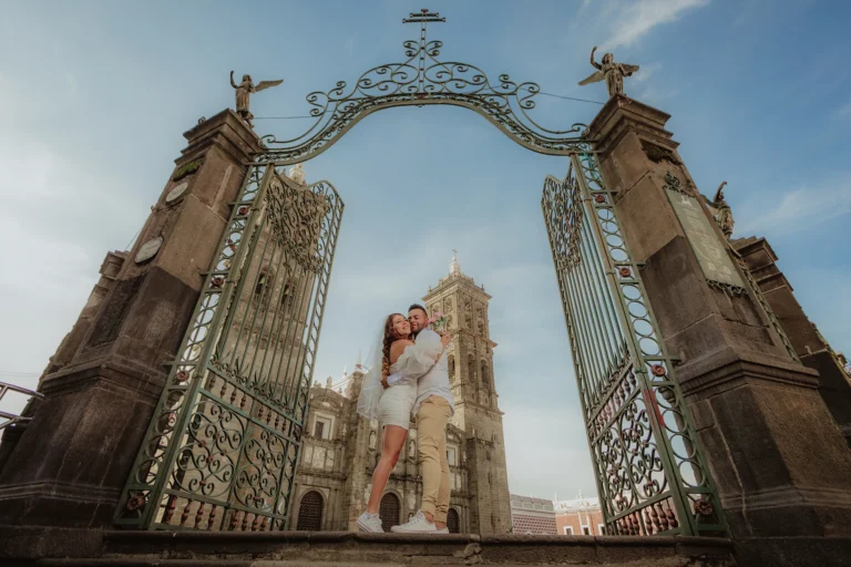 Fotografía de bodas de una pareja de novios abrazándose en la entrada de la Catedral de Puebla. Retrato editorial con arquitectura histórica, luz natural y una composición elegante.