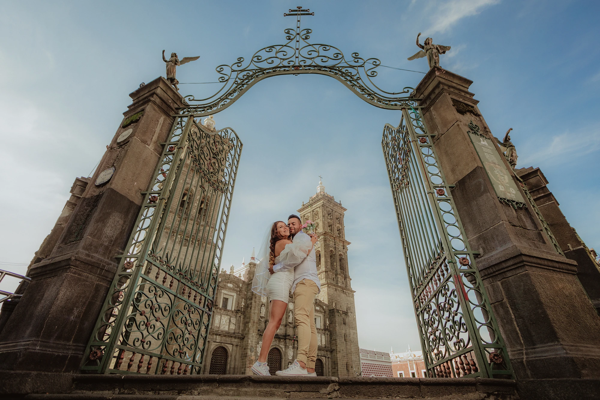 Fotografía de bodas de una pareja de novios abrazándose en la entrada de la Catedral de Puebla. Retrato editorial con arquitectura histórica, luz natural y una composición elegante.
