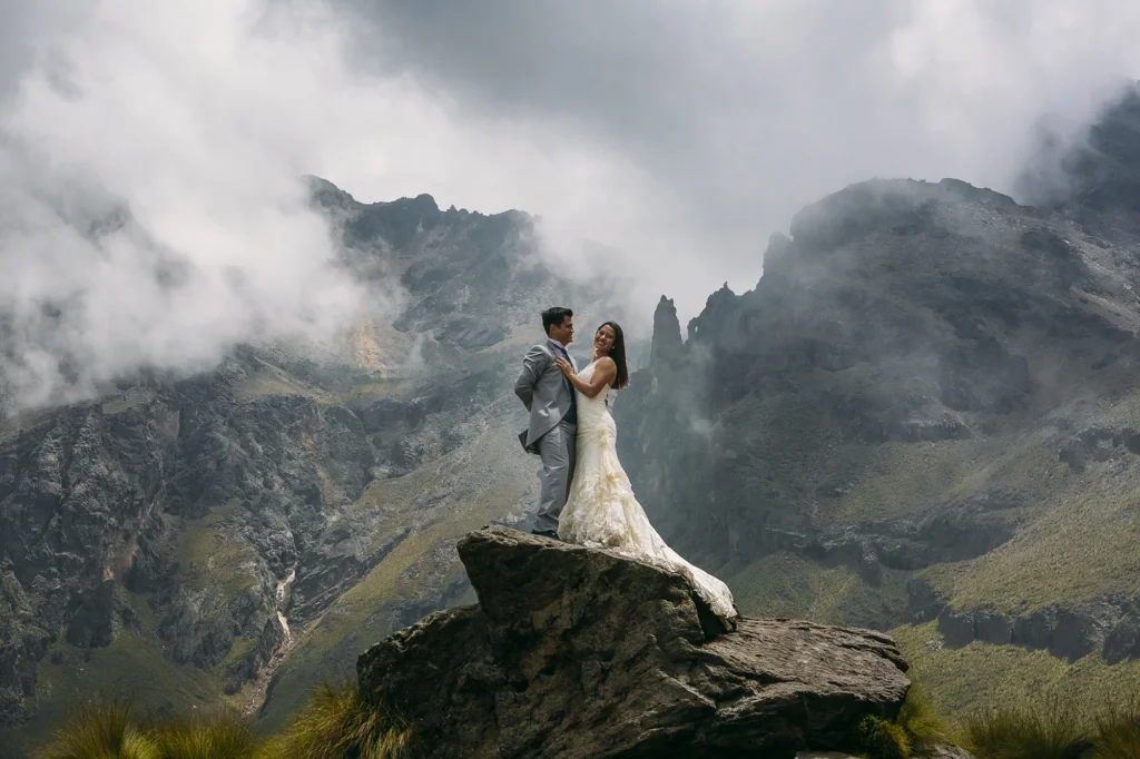 Retrato de una pareja de novios sobre una roca con el volcán Iztaccíhuatl al fondo. Fotografía de bodas editorial que combina paisaje, luz natural y una composición artística en alta montaña.