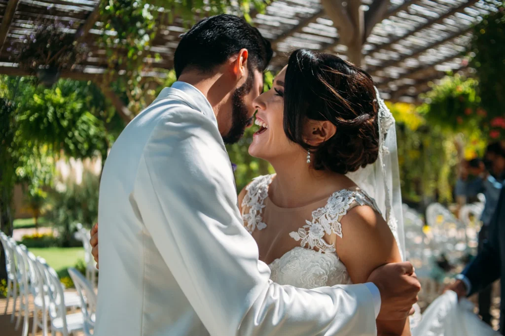Novia sonriendo con felicidad junto a su novio en el altar durante la ceremonia, compartiendo un momento lleno de amor y emoción.
