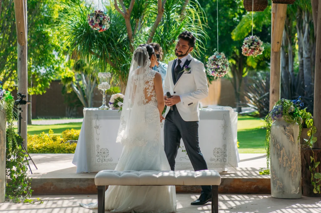 Novio en el altar con una expresión de felicidad y emoción, al borde de las lágrimas mientras espera a su novia durante la ceremonia de boda.