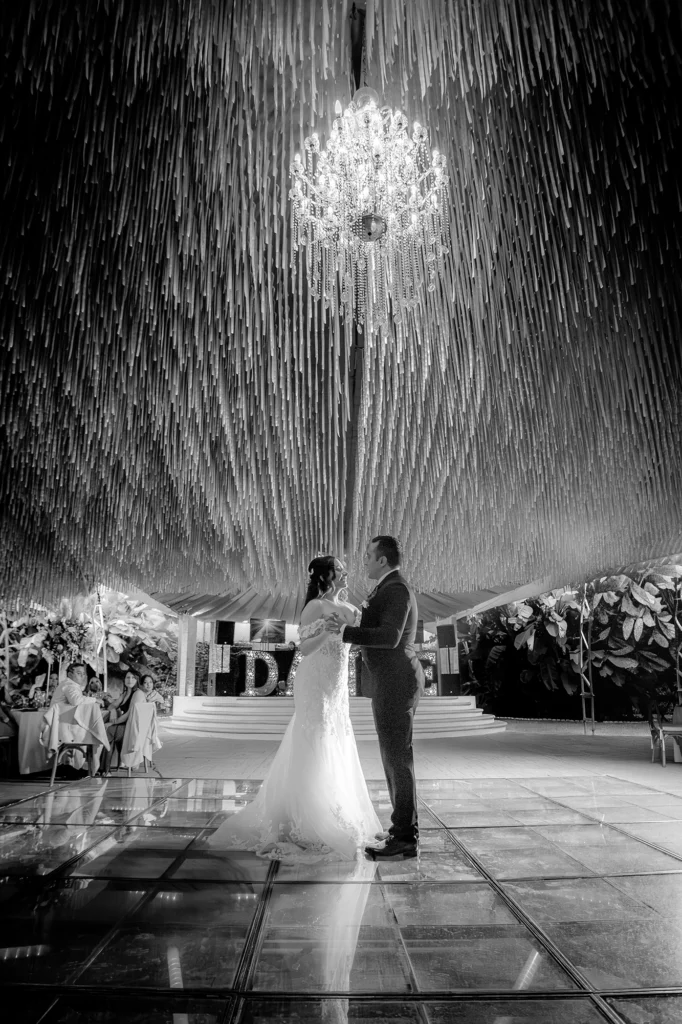 Novios durante su primer baile en una elegante recepción de boda con pista de cristal y candelabro en Puebla.